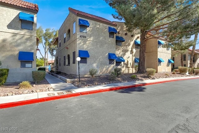 view of property exterior with a tile roof and stucco siding