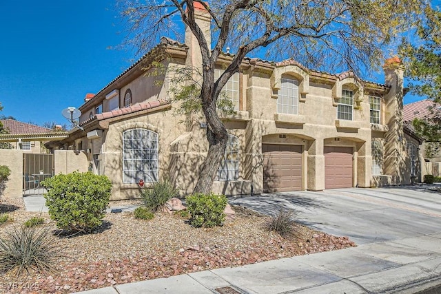 mediterranean / spanish-style home featuring concrete driveway, stucco siding, a chimney, a garage, and a gate