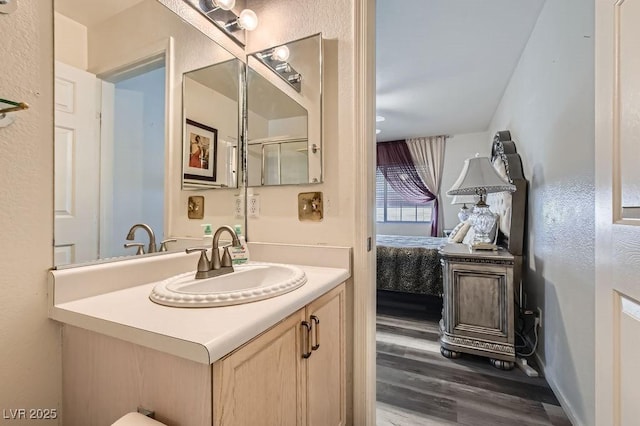 ensuite bathroom featuring vanity, ensuite bath, and wood finished floors