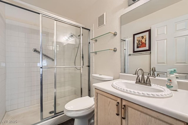 full bathroom with vanity, toilet, visible vents, and a stall shower