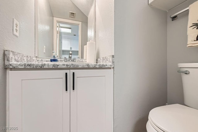 half bath with visible vents, toilet, vanity, and lofted ceiling