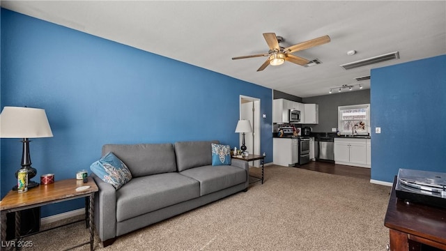 living area with dark colored carpet, visible vents, track lighting, and a ceiling fan