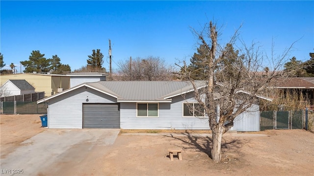 single story home with a garage, driveway, metal roof, and fence