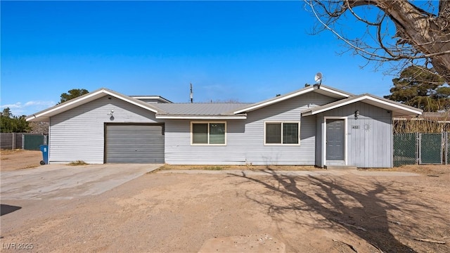 ranch-style house featuring concrete driveway, fence, metal roof, and a garage