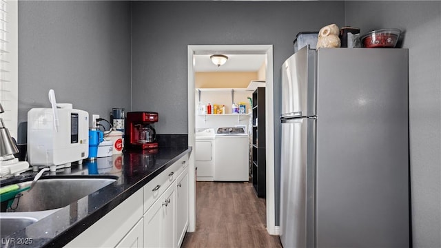 kitchen with dark stone countertops, wood finished floors, freestanding refrigerator, separate washer and dryer, and white cabinetry