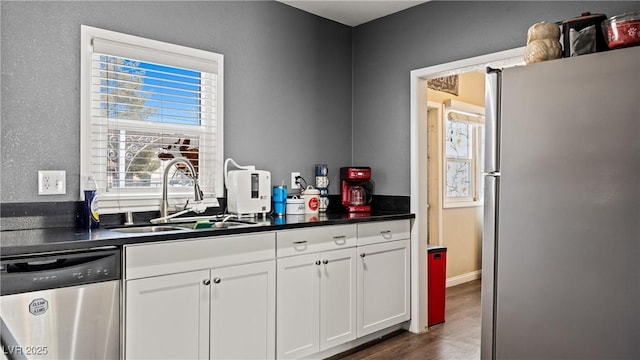 kitchen featuring dark countertops, white cabinetry, stainless steel appliances, and a sink