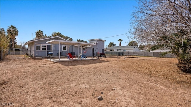 rear view of property featuring board and batten siding, a patio area, and a fenced backyard