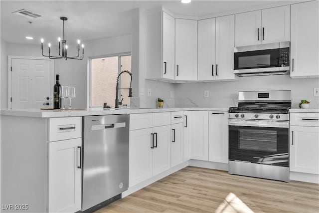 kitchen featuring stainless steel appliances, light countertops, visible vents, light wood-style flooring, and white cabinetry