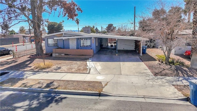 view of front of house with a carport, concrete driveway, and fence