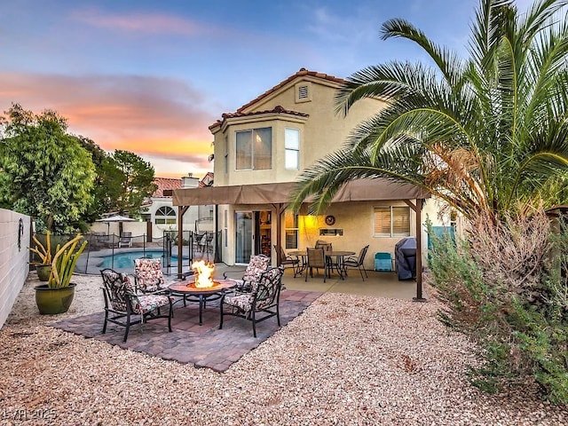 back of property at dusk with a patio area, a fenced backyard, a fenced in pool, and stucco siding