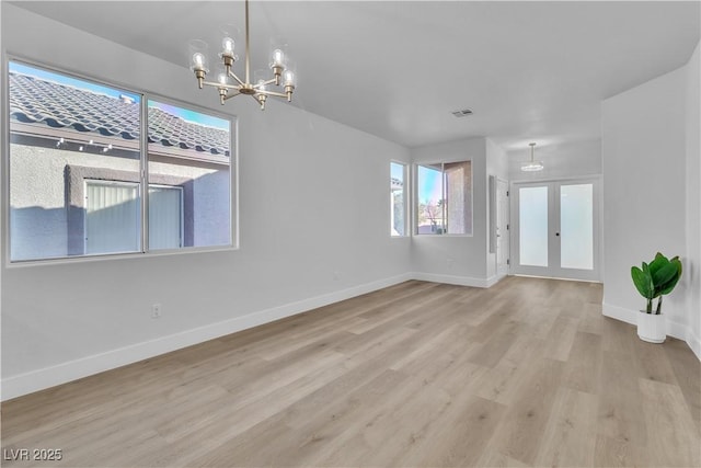 unfurnished room with light wood finished floors, visible vents, baseboards, french doors, and a notable chandelier