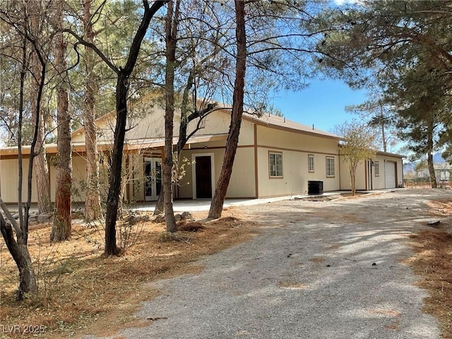 ranch-style home featuring central air condition unit, driveway, an attached garage, and french doors