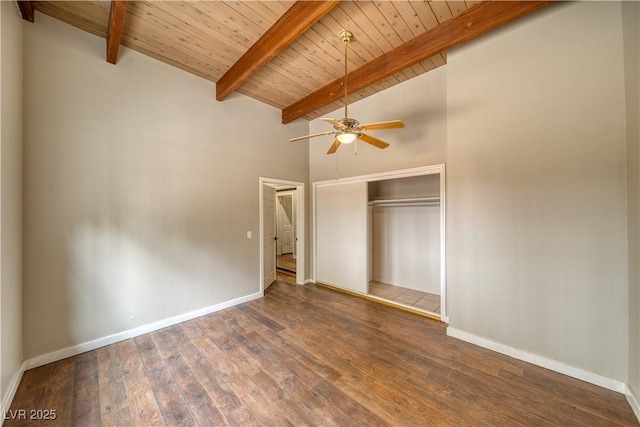 unfurnished bedroom featuring dark wood-type flooring, beam ceiling, a closet, and baseboards