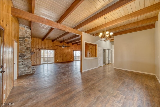 unfurnished living room with baseboards, dark wood-style floors, wood walls, beam ceiling, and ceiling fan with notable chandelier