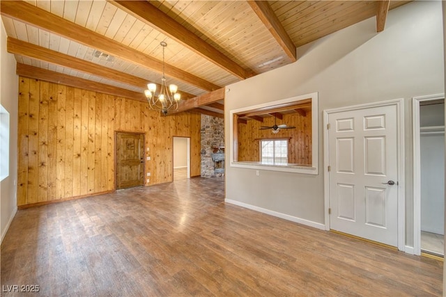 unfurnished living room featuring wooden walls, wood finished floors, wooden ceiling, beamed ceiling, and baseboards