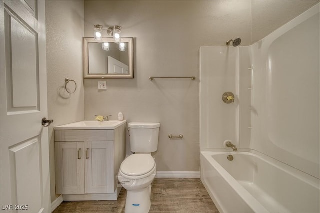 full bathroom with toilet, wood finished floors, vanity, baseboards, and washtub / shower combination