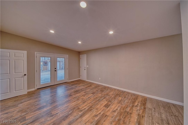 unfurnished room featuring lofted ceiling, baseboards, wood finished floors, and french doors