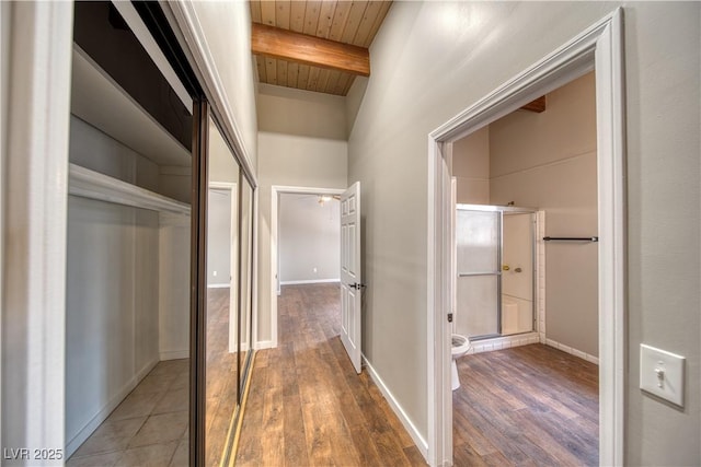 corridor with wood ceiling, baseboards, beamed ceiling, and wood finished floors