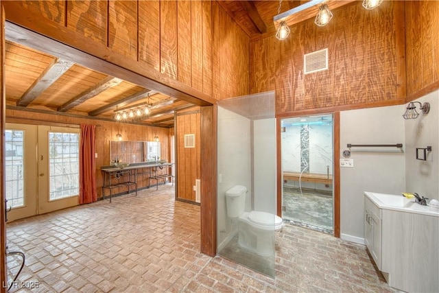 bathroom featuring wooden ceiling, toilet, wood walls, visible vents, and beamed ceiling