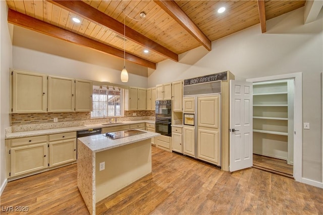 kitchen with a kitchen island, light stone countertops, black appliances, pendant lighting, and a sink