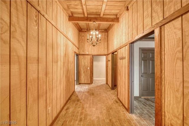 corridor featuring wood ceiling, brick floor, beam ceiling, wood walls, and a notable chandelier