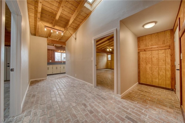 hallway featuring brick floor, a skylight, wood ceiling, and baseboards