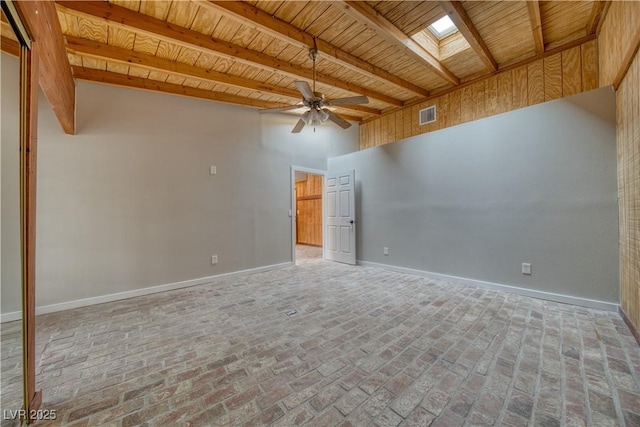 unfurnished room with a skylight, beam ceiling, visible vents, ceiling fan, and baseboards