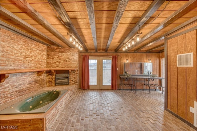 unfurnished living room featuring brick wall, beam ceiling, brick floor, and visible vents