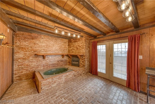 unfurnished living room with brick floor, french doors, wooden ceiling, and beamed ceiling