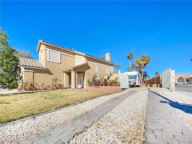 mediterranean / spanish house featuring a tiled roof, a front lawn, and stucco siding