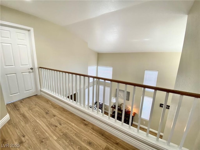 hall featuring lofted ceiling, light wood finished floors, and baseboards