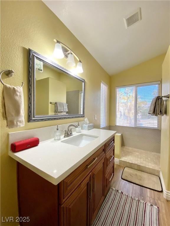 bathroom featuring visible vents, vaulted ceiling, wood finished floors, and vanity