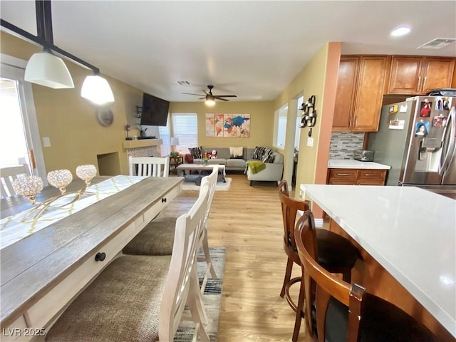 dining space featuring light wood-style floors, visible vents, and ceiling fan