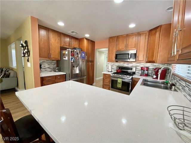 kitchen featuring stainless steel appliances, a peninsula, a sink, visible vents, and light countertops