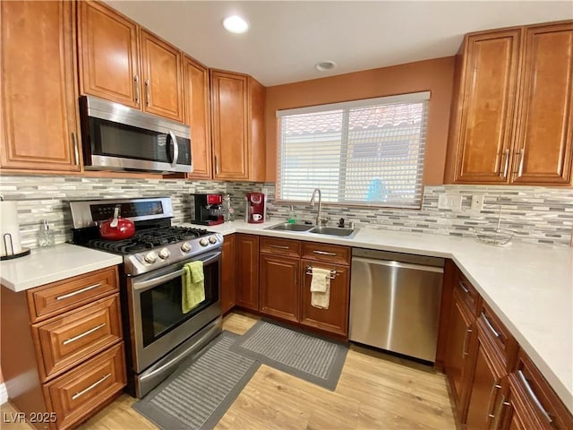 kitchen featuring stainless steel appliances, a sink, light countertops, and brown cabinets