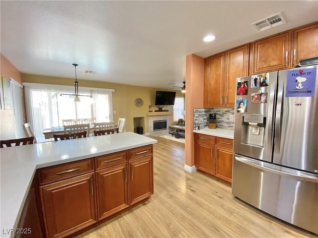 kitchen featuring light countertops, stainless steel refrigerator with ice dispenser, visible vents, and pendant lighting