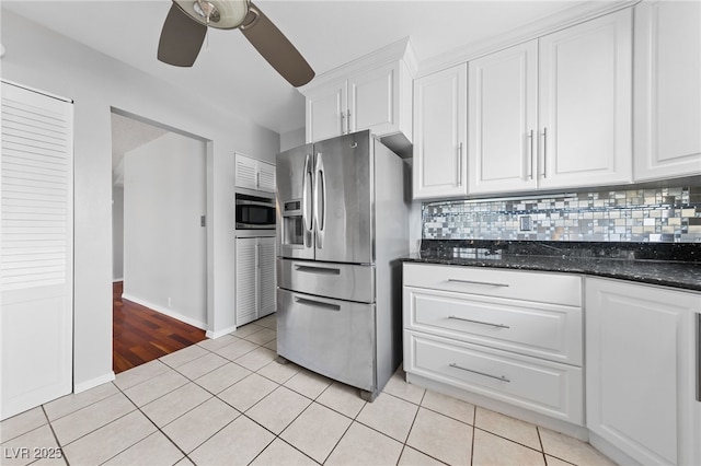 kitchen featuring light tile patterned floors, appliances with stainless steel finishes, dark stone counters, and white cabinets