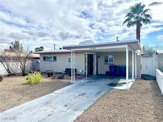 view of front facade with a gate, fence, driveway, and stucco siding