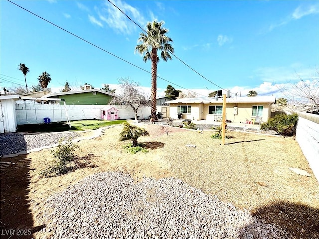 rear view of house featuring a fenced backyard and a lawn