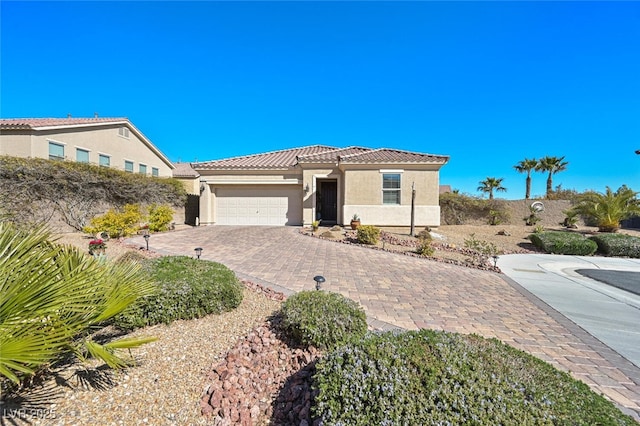 view of front of property with decorative driveway, a tile roof, stucco siding, fence, and a garage