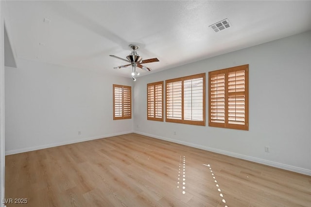 empty room featuring a ceiling fan, baseboards, visible vents, and wood finished floors