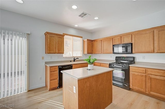 kitchen featuring visible vents, light countertops, light wood-type flooring, a center island, and black appliances