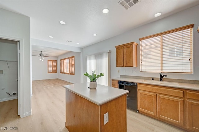 kitchen with black dishwasher, visible vents, a kitchen island, light wood-type flooring, and a sink