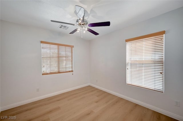 empty room with ceiling fan, light wood-style flooring, visible vents, and baseboards