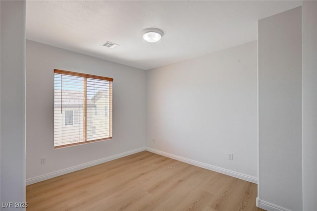 empty room with baseboards, visible vents, and light wood-style floors