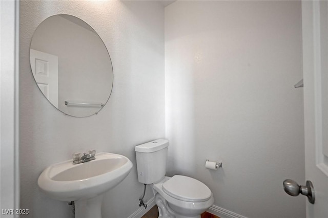 bathroom featuring toilet, baseboards, and a sink