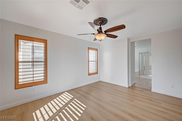 empty room featuring a ceiling fan, light wood-style flooring, visible vents, and baseboards