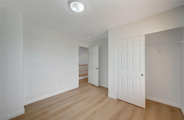 unfurnished bedroom with a closet, baseboards, and wood finished floors