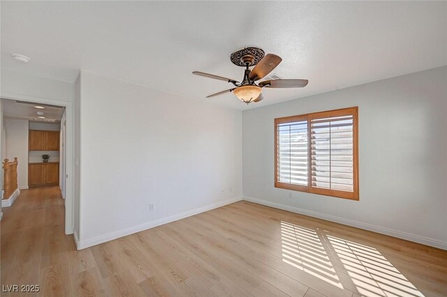 spare room featuring light wood-style floors, baseboards, and a ceiling fan