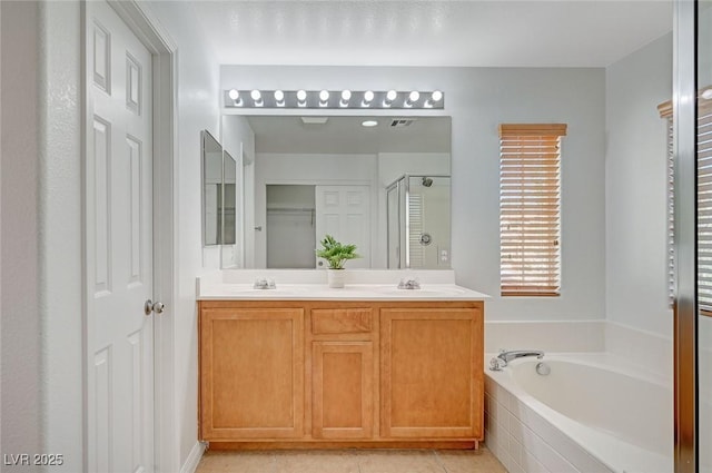 bathroom with a garden tub, double vanity, a stall shower, a sink, and tile patterned floors